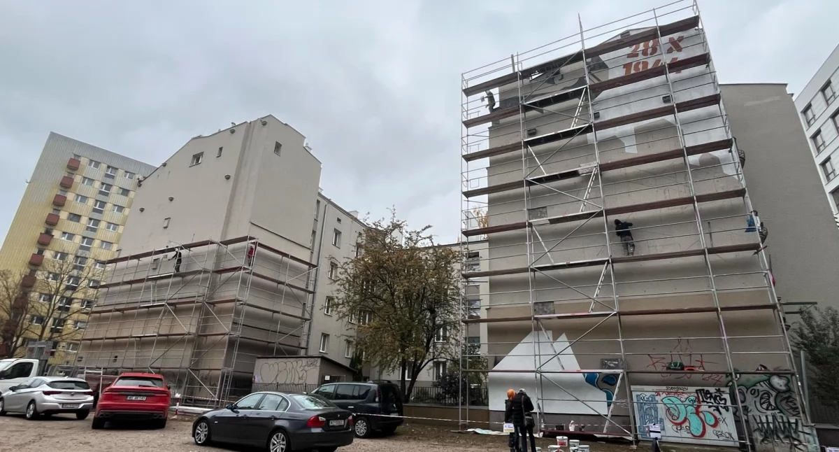 Zdjęcie fasady bloku, na której Zbigniew Komosa maluje mural 