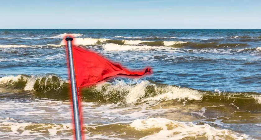 Czerwona flaga na plaży nad Bałtykiem oznaczająca zakaz kąpieli z powodu wysokich fal